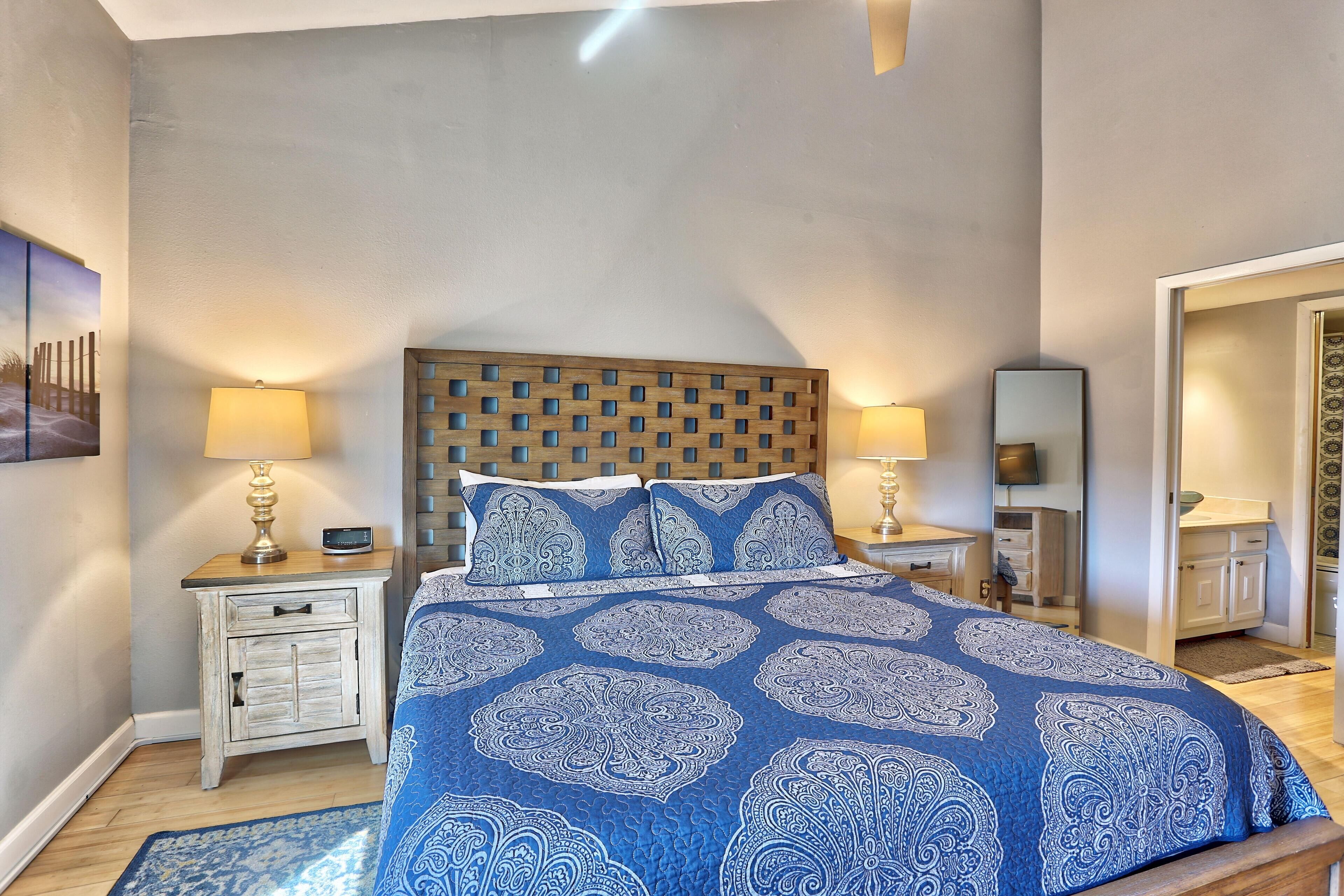Une chambre à coucher avec un lit, des tables de chevet, une tête de lit en bois et une couvre-lit à motifs.