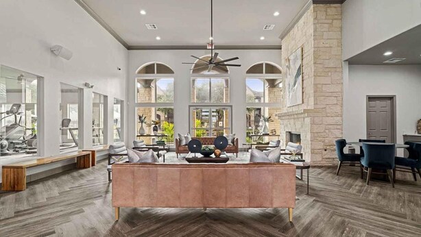 A spacious living area with a large central seating area, a fireplace, and a view of the outdoors through large windows. - Landing | Stunning 1BD, Courtyard, Clubhouse (Austin)