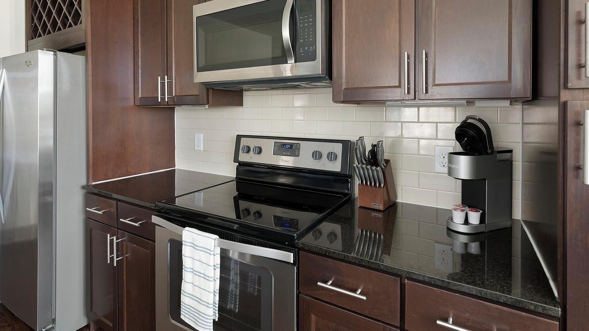 Een moderne keuken met roestvrijstalen apparatuur, houten kastjes en een zwart aanrecht.