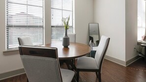 Ein Essbereich mit einem runden Tisch, vier Stühlen, einer Pflanze in einer Vase und einem Spiegel an der Wand.