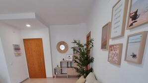 A modern living room with a sofa, a wooden door, a mirror, and framed pictures on the wall.