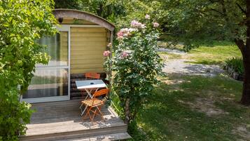 A wooden deck with a table and chairs, a small shed, and a rose bush.