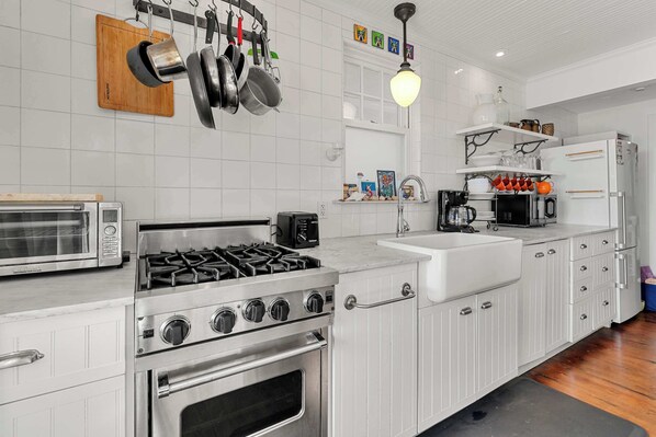 A kitchen with white cabinets, a gas stove, a microwave, and a sink. - Waterfront with Private Beach, Stunning Views! (Provincetown)