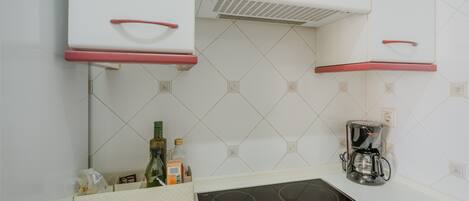 A kitchen with white cabinets, a built-in stove, and a coffee maker.