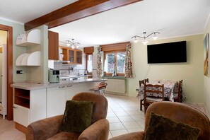 A kitchen with a central island, wooden cabinets, and a dining area with a table and chairs. - Holiday Home 'La Maisonnette' with Mountain View, Private Garden & Wi-Fi (Maisonasse)