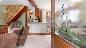 A modern kitchen with wooden cabinets, a staircase, and a glass door with a plant. - Holiday Home 'La Maisonnette' with Mountain View, Private Garden & Wi-Fi (Maisonasse)