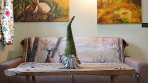 A wooden table with a gnome figurine in front of a couch with a patterned throw. - Holiday Home 'La Maisonnette' with Mountain View, Private Garden & Wi-Fi (Maisonasse)
