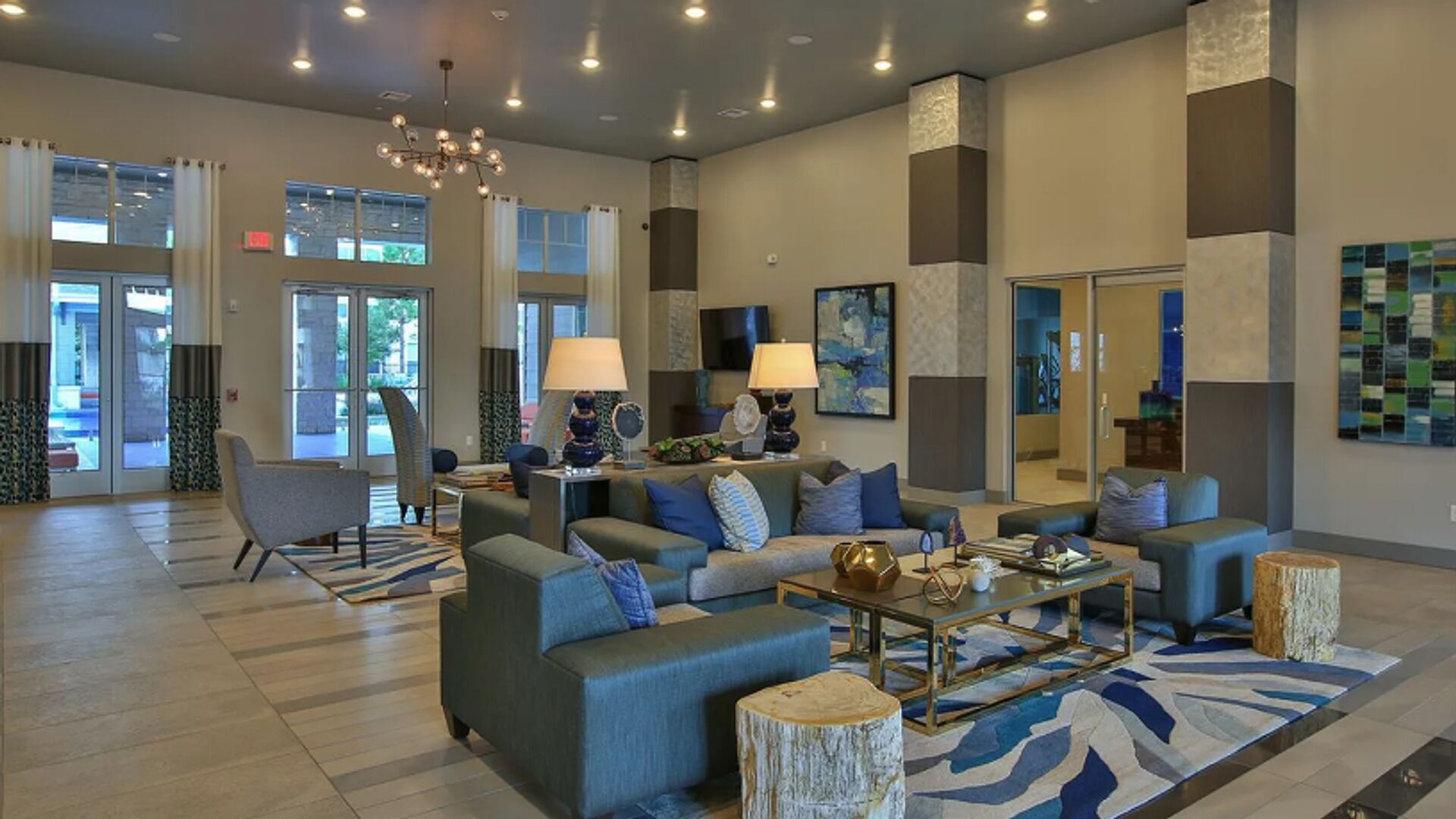 Eine großzügige Lobby mit modernem Design, ausgestattet mit einer Sitzecke, Sofas, Sesseln, einem Couchtisch und einem Kronleuchter.