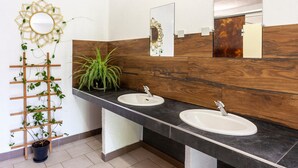 Een badkamer met twee wastafels, een houten wastafelmeubel, een spiegel en een decoratieve plantenwand.