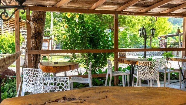 Een houten pergola met een tafel en stoelen eronder.