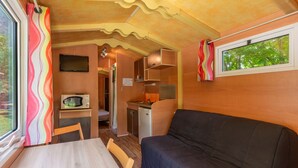 Een compact camperinterieur met een kitchenette, een eethoek en een zithoek.