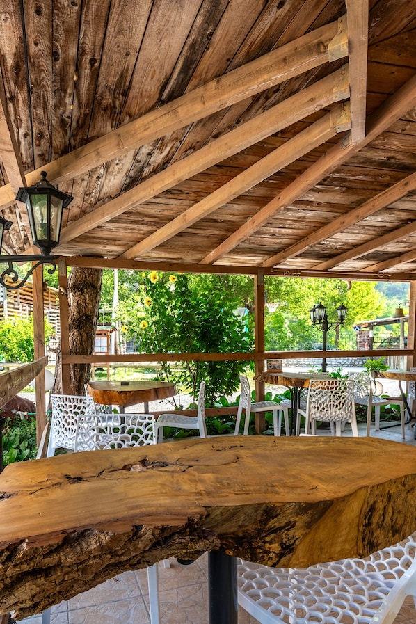 Una pérgola de madera con una mesa y sillas debajo.