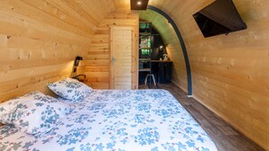A wooden cabin room with a bed, a desk, and a TV mounted on the wall. - Tiny Home 'Le Pod 3' with Mountain View, Wi-Fi and Air Conditioning (Touët-sur-Var)