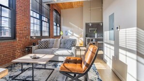 A modern living room with a leather chair, a grey sofa, and a coffee table. - Landing | Stunning 1BD, Gym, Game Room (New Haven)