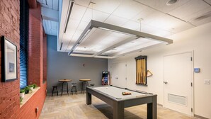 Une table de billard avec des tabourets, une table de ping-pong et une porte dotée d’un panneau de sécurité.