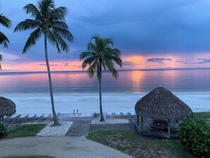 A beach view with palm trees, a wooden deck, and thatched-roof structures. - BREATHTAKING VIEWS OF THE SHORELINE
 SAND SCULPTING CHAMPIONSHIP NOV. 19-23 (fort myers beach)