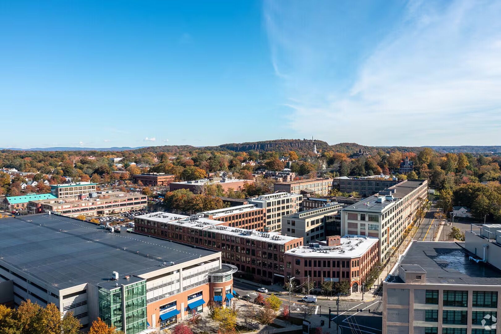 A cityscape with a mix of modern and historic buildings, a prominent church steeple, and a hilly backdrop.