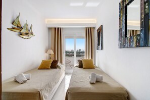 A hotel room with two beds, a view to the outside, and a decorative sailboat on the wall. - Apartment 'Golf y Mar - T2' with Shared Pool, Wi-Fi and Air Conditioning (Vilamoura)