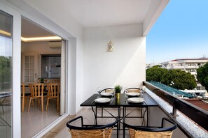 A balcony with a table set for dining, a small plant, and a lantern. - Apartment 'Golf y Mar - T2' with Shared Pool, Wi-Fi and Air Conditioning (Vilamoura)