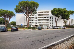 A multi-story building with a parking area in front. - Apartment 'Golf y Mar - T2' with Shared Pool, Wi-Fi and Air Conditioning (Vilamoura)
