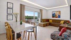 Ein modernes Wohnzimmer mit Essbereich, einer Sofagarnitur und einem Gemälde an der Wand.