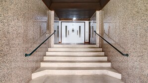 Eine Treppe mit Granitwänden und Metallgeländern, die zu einer Tür führt.