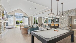 A spacious living room with a pool table, comfortable seating, and a stone accent wall. - Landing | Stylish 1BD, Gym, Clubhouse (Norfolk)