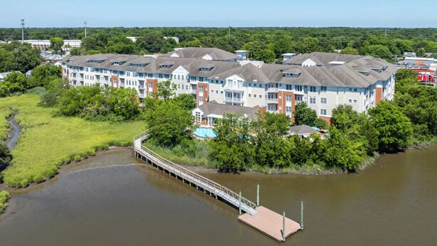 A multi-story residential building with a dock extending into a river. - Landing | Stylish 1BD, Gym, Clubhouse (Norfolk)