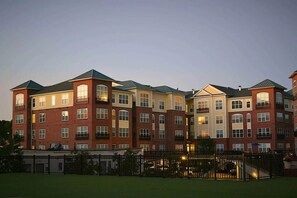 A multi-story hotel with a brick facade, multiple balconies, and a gated entrance.