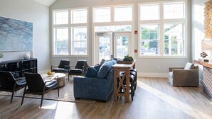 Un salon spacieux avec un haut plafond, de grandes fenêtres, une cheminée moderne et un coin repas.