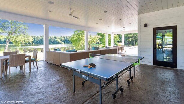 A spacious outdoor area with a ping pong table, seating, and a view of a lake. - Landing | Beautiful 2BD, Clubhouse, Gym (Windsor)