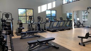 Un gimnasio con cintas de correr, elípticas y equipo de levantamiento de pesas.