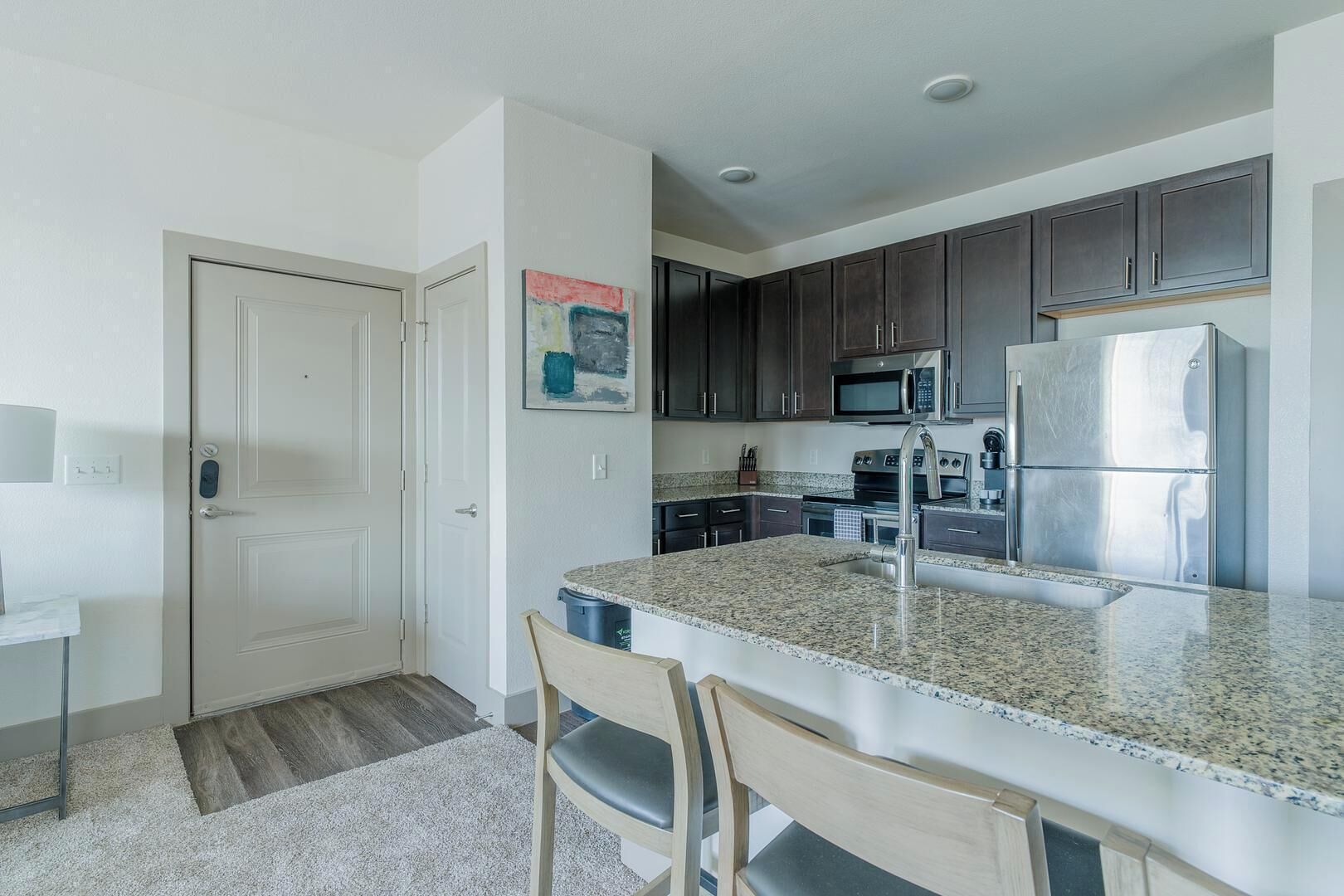 A modern kitchen with granite countertops, stainless steel appliances, and dark wooden cabinets.