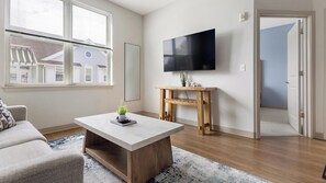 A modern living room with a flat-screen TV, a coffee table, and a sofa.