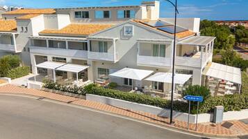 Ein modernes Hotel mit mehreren Balkonen, Sitzgelegenheiten im Freien und freiem Blick auf das Meer.