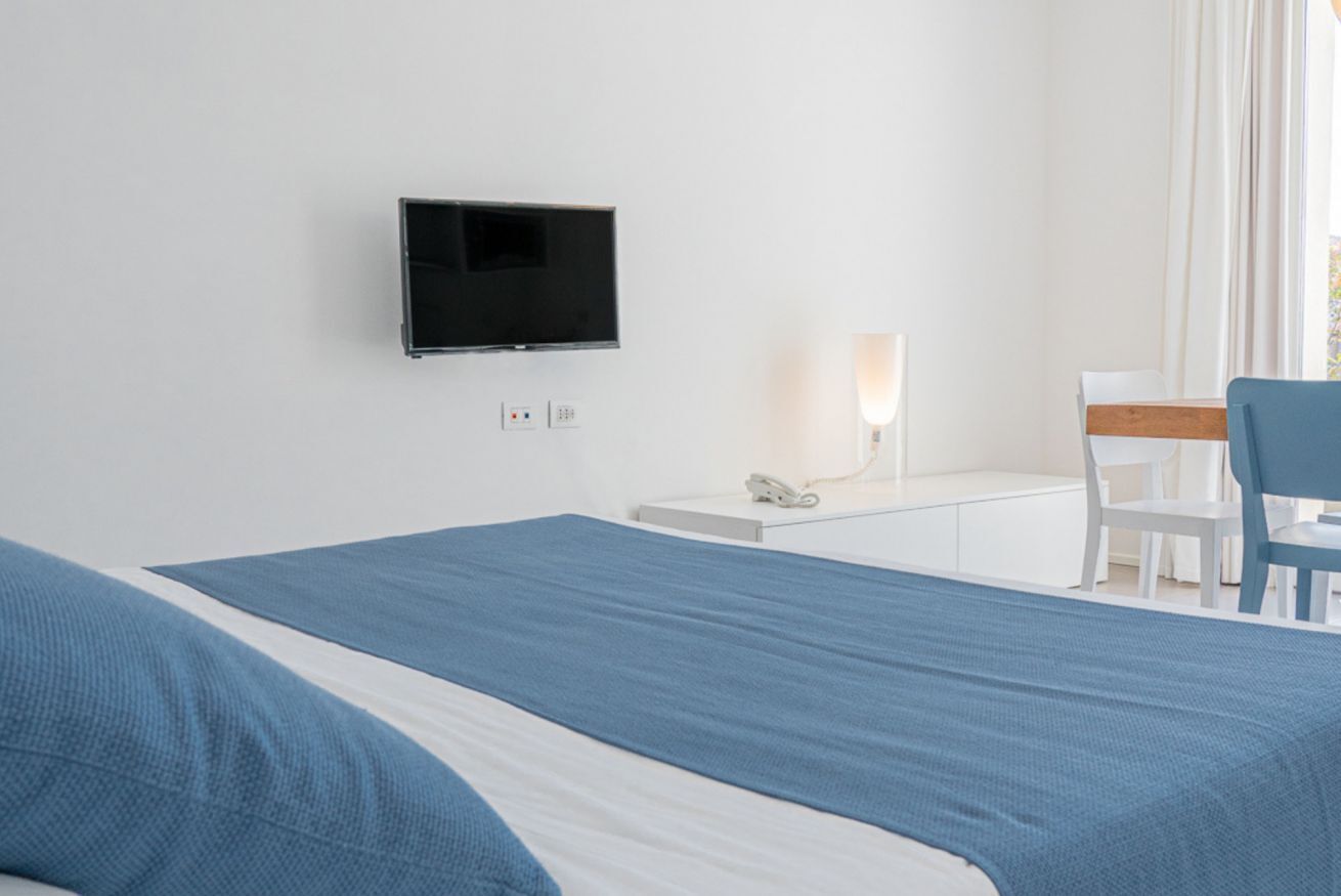 Ein Hotelzimmer mit einem Bett, einem Schreibtisch, einem Sessel, einem Fernseher und einem Telefon.