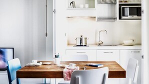 Una cocina moderna con armarios blancos, una mesa de comedor de madera y una cafetera.
