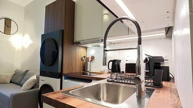 Una cocina compacta con un lavamanos, encimera de madera y electrodomésticos modernos.