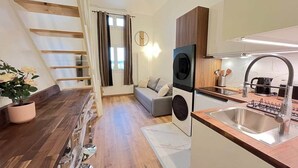 Una cocina moderna con horno empotrado, un lavamanos y una zona de comedor con mesa y sillas.