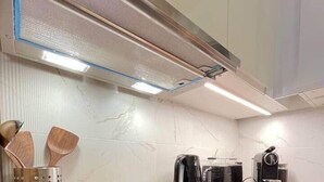 Una cocina moderna con encimera negra, electrodomésticos de acero inoxidable y utensilios de madera.