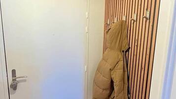 A hallway with a wooden slat wall, a white door, and a coat hanging on a hook.