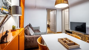 A modern living room with a sofa, a dining table, and a TV. - YiD Lungarno Cellini retreat (Florence)