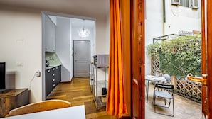 A modern living space with a kitchen, dining area, and a small outdoor seating area with a view of greenery. - YiD Lungarno Cellini retreat (Florence)