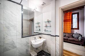 A modern bathroom with a white sink, glass shelves, and a large mirror. - YiD Lungarno Cellini retreat (Florence)