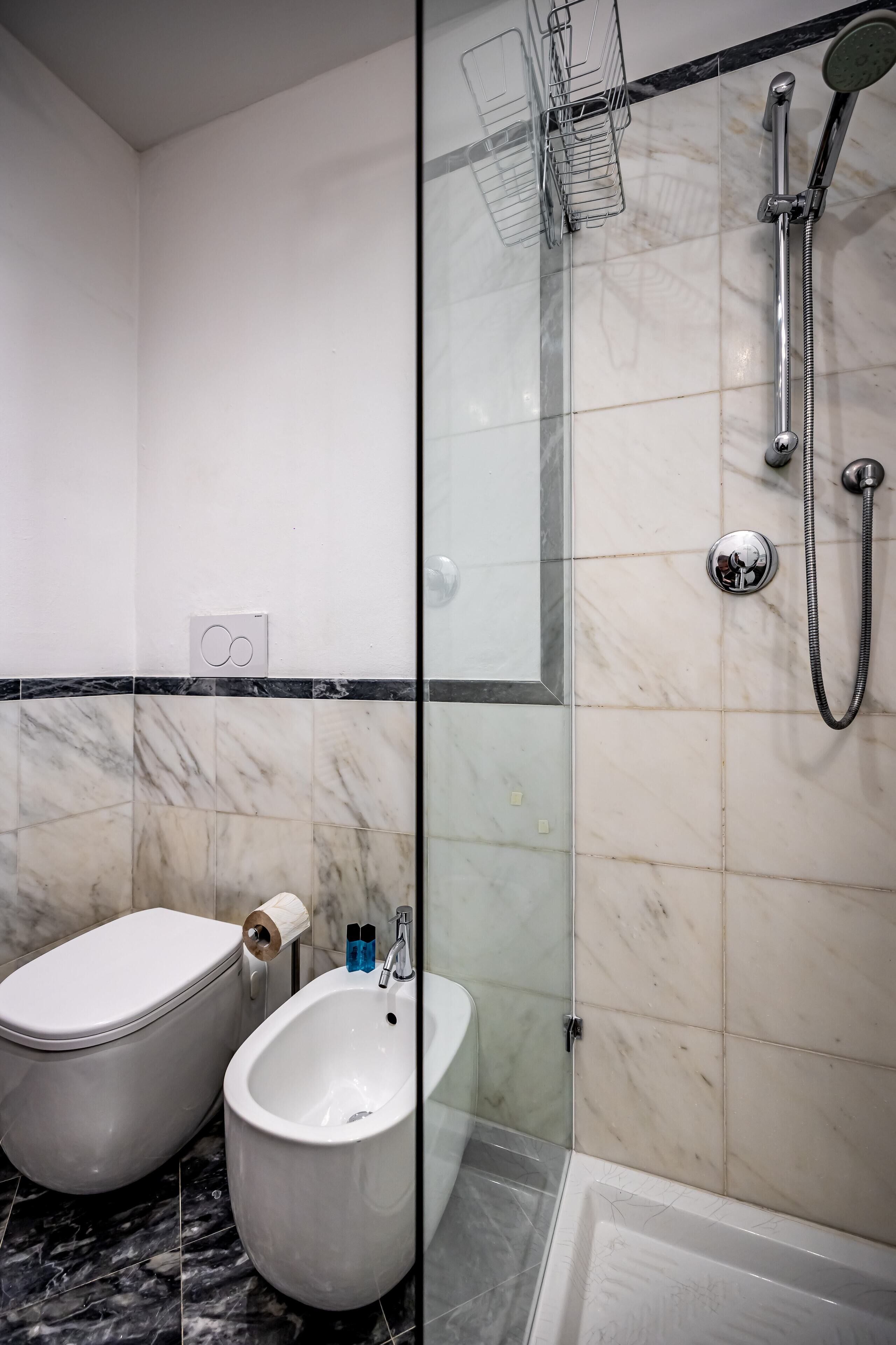 Une salle de bain moderne équipée de toilettes, d’un bidet et d’une douche à l’italienne.