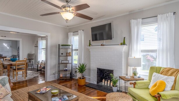 A spacious living room with a fireplace, a ceiling fan, and a television mounted above it. - A beautiful balanced 2-bedroom bungalow near quaint downtown New Bern (New Bern)