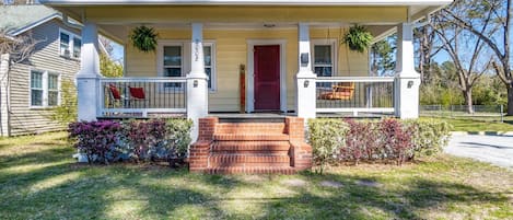 A two-story house with a front porch, a red door, and a mailbox.