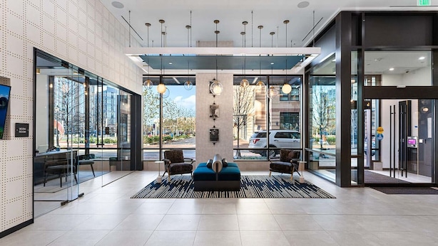 Eine moderne Lobby mit einer Rezeption, einer Sitzecke und großen Fenstern mit Blick ins Freie.