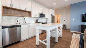 A modern kitchen with white cabinets, stainless steel appliances, and a central island. - Landing | Amazing 2BD, Clubhouse, Courtyard (Alexandria)