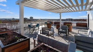 A rooftop terrace with outdoor seating, a pergola, and a view of the cityscape. - Landing | Modern 2BD, Courtyard, Gym (Alexandria)